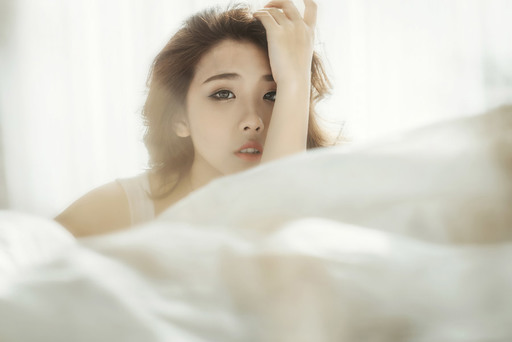 顔に手をあてる女性の写真