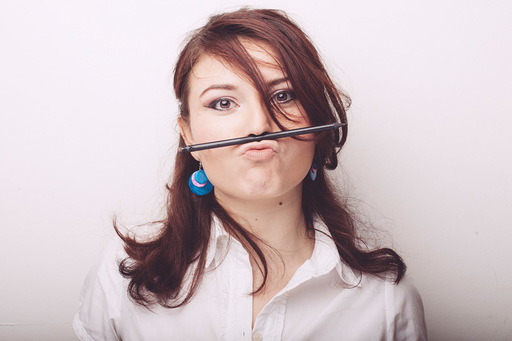 鼻に鉛筆を挟む女性の写真