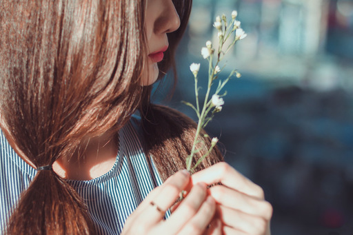 小さな花を持つ女性の横顔の写真