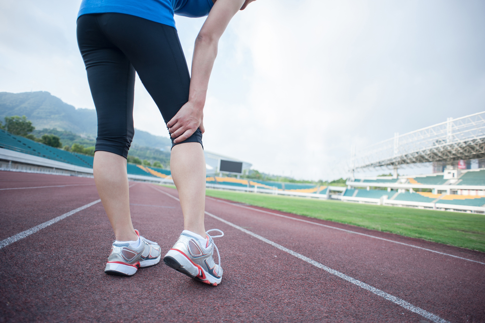 woman runner hold her injured leg on track