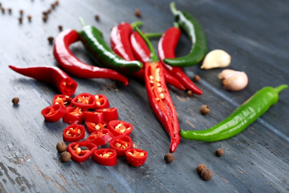 Hot peppers with spices on wooden table close up