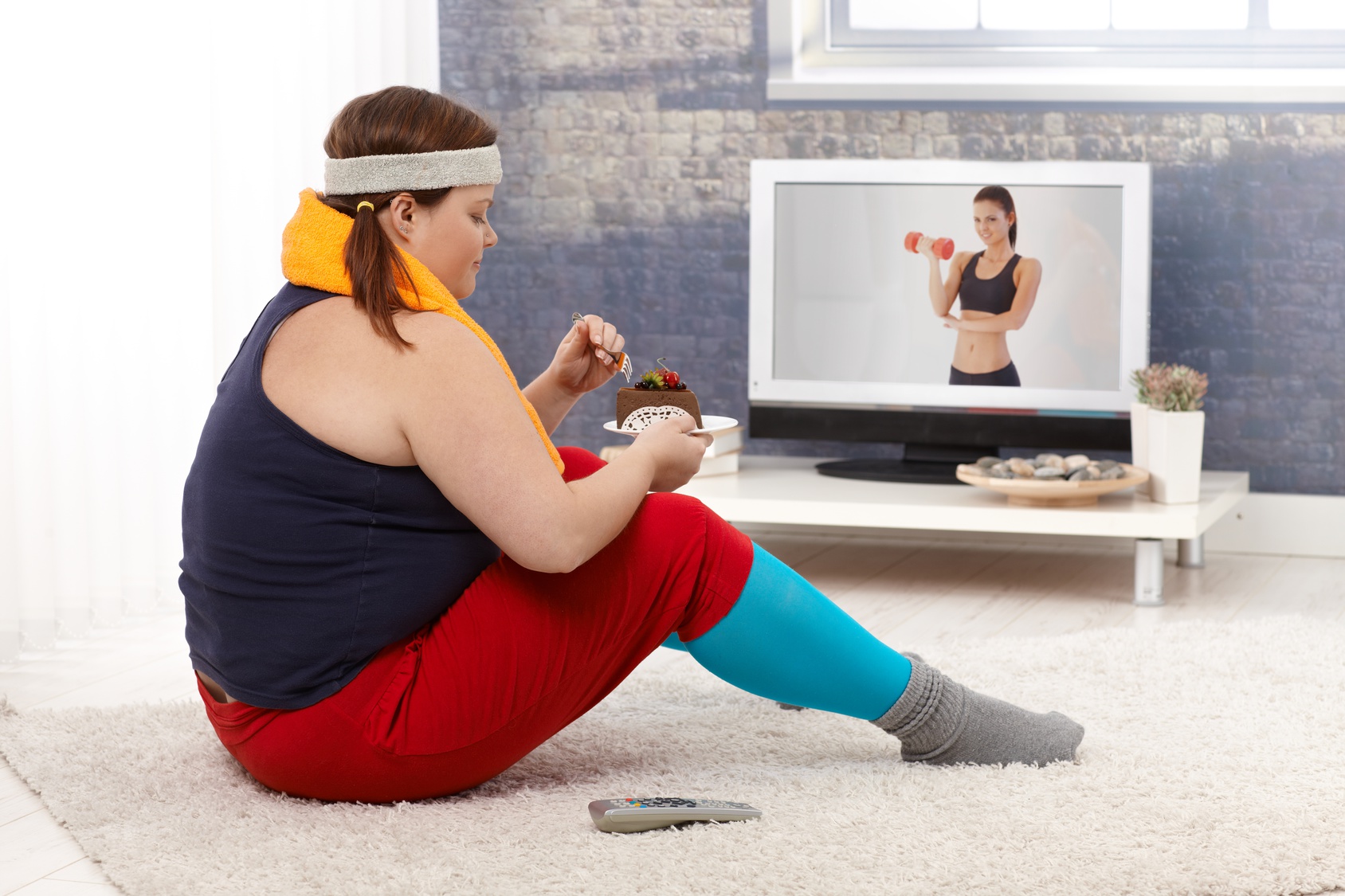 Fat woman eating chocolate cake in sportswear