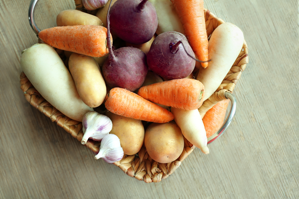 Root vegetables in basket on wooden table