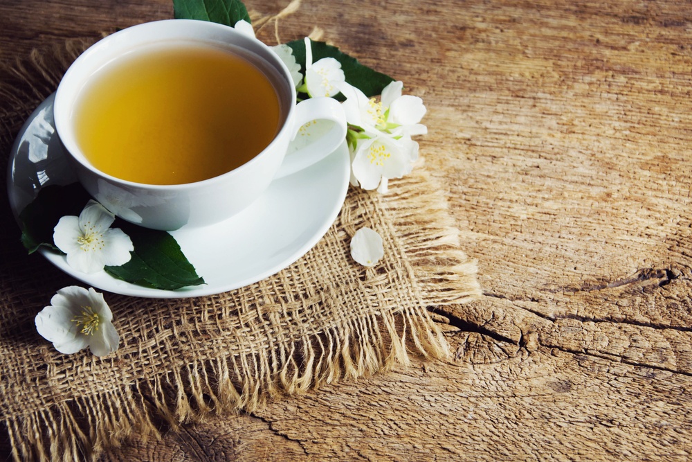 A cup of green tea with jasmine on wooden background.