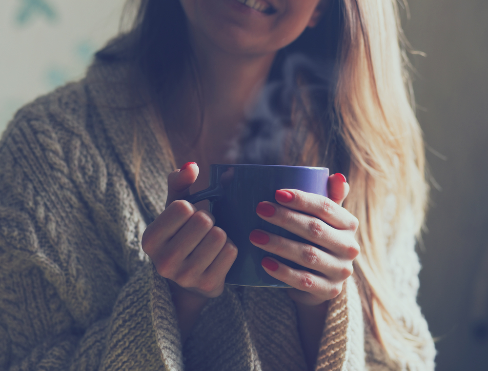hands holding hot cup of coffee or tea in morning