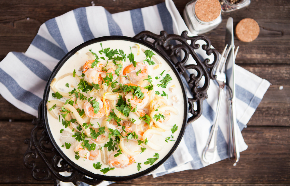 seafood - shrimp and squid with white cream sauce on frying pan, rustik style