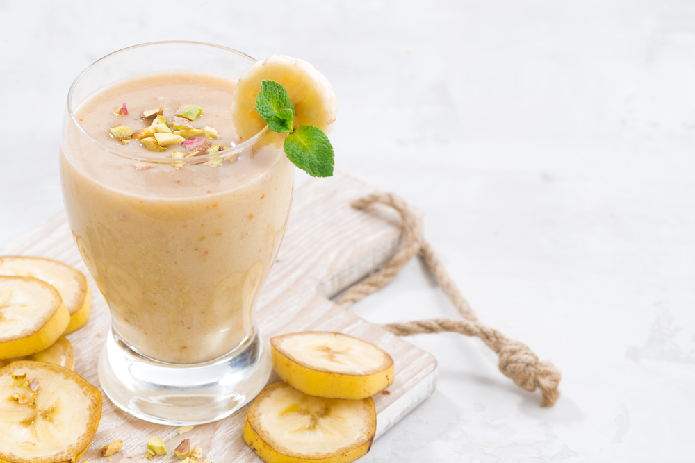 banana milkshake in a glass on white wooden board, closeup