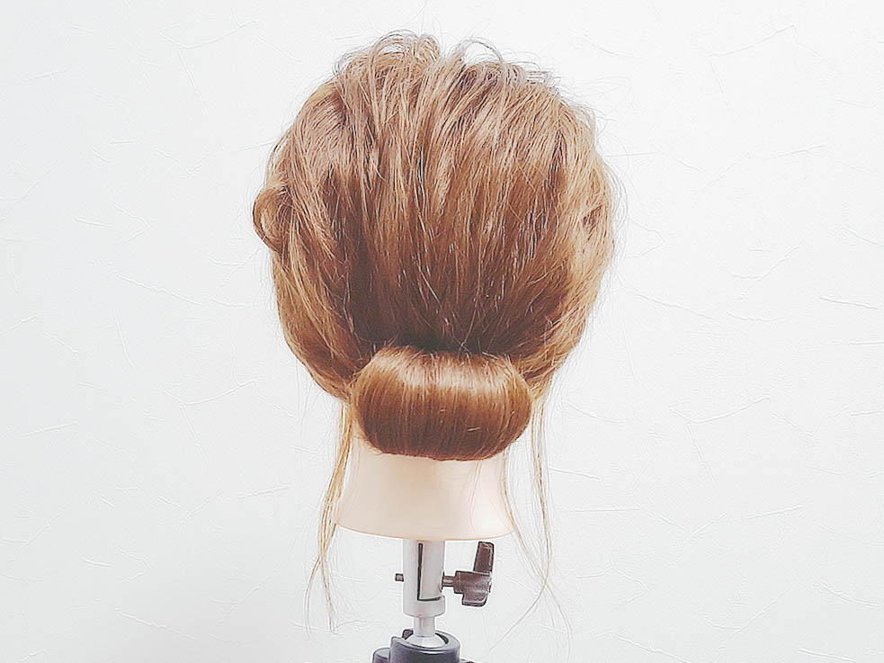 結んだ毛束の先を外巻きにくるくると巻いていきシニヨンを作り、アメピンを使って固定します